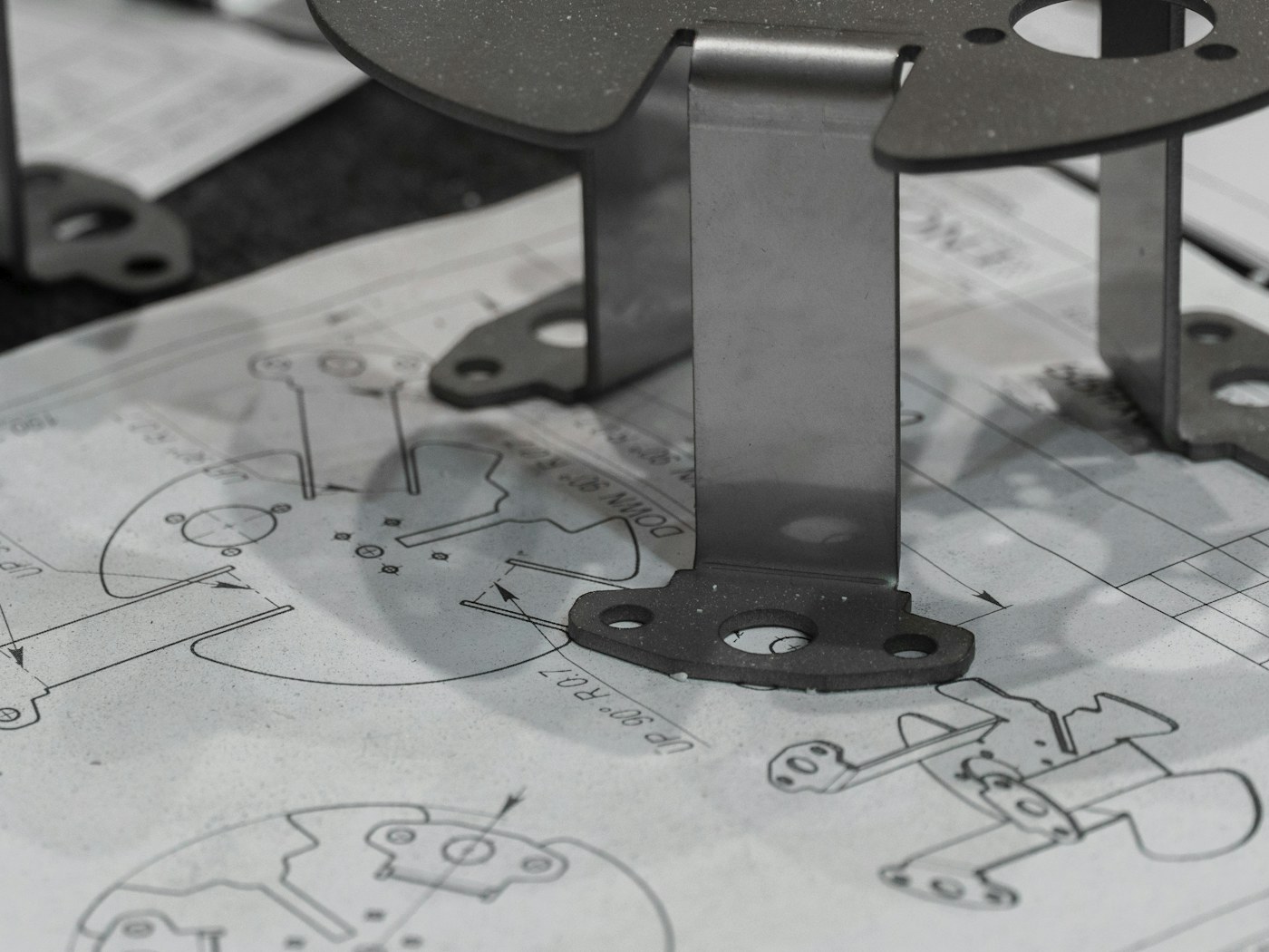 Componentes metálicos apoiados sobre desenhos técnicos de engenharia